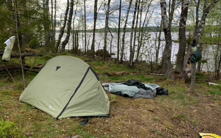 Teltan pystytys metsässä järven rannalla